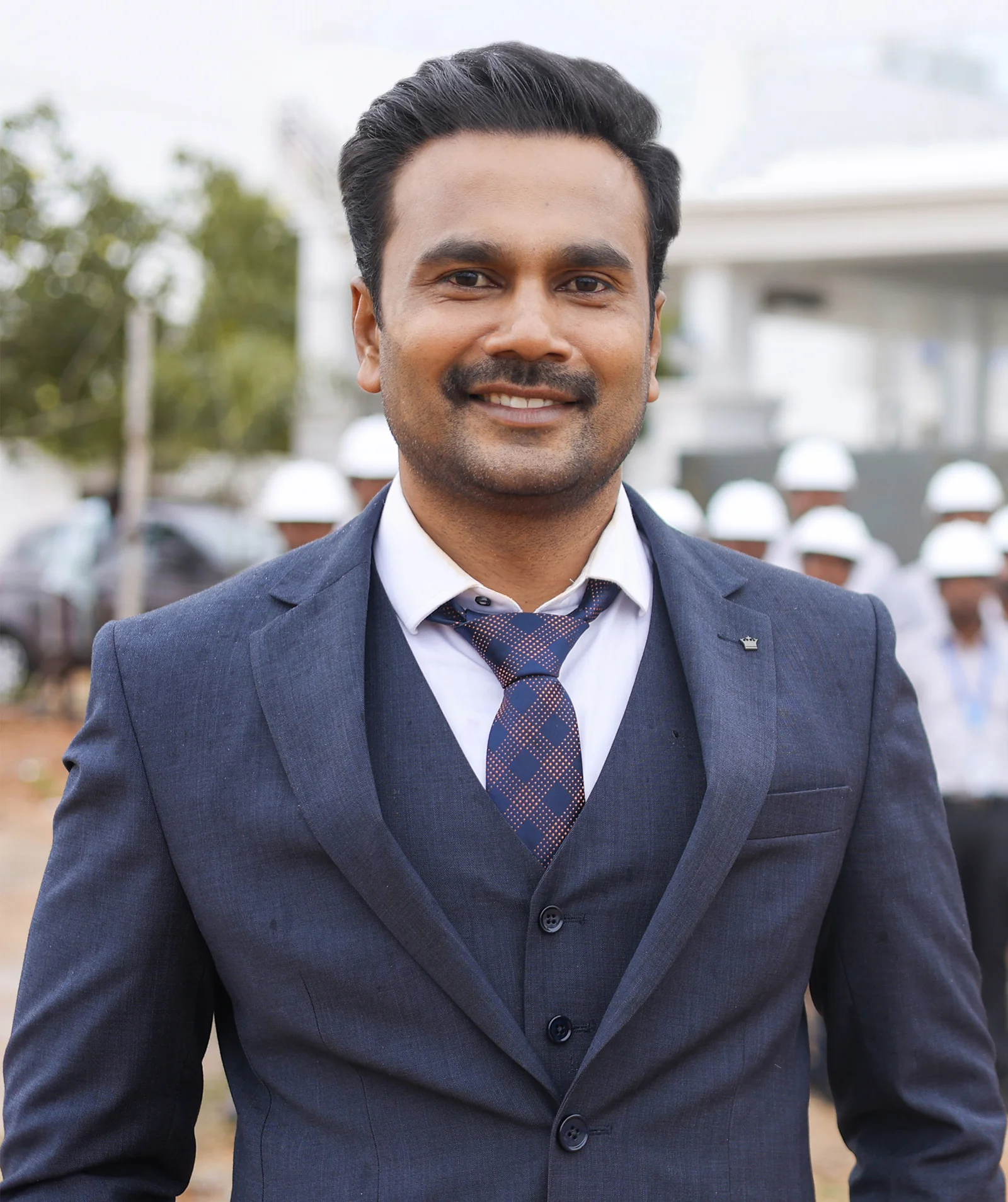 Portrait of the Founder and Managing Director of Jehovah Builders, on site in a three-piece suit.