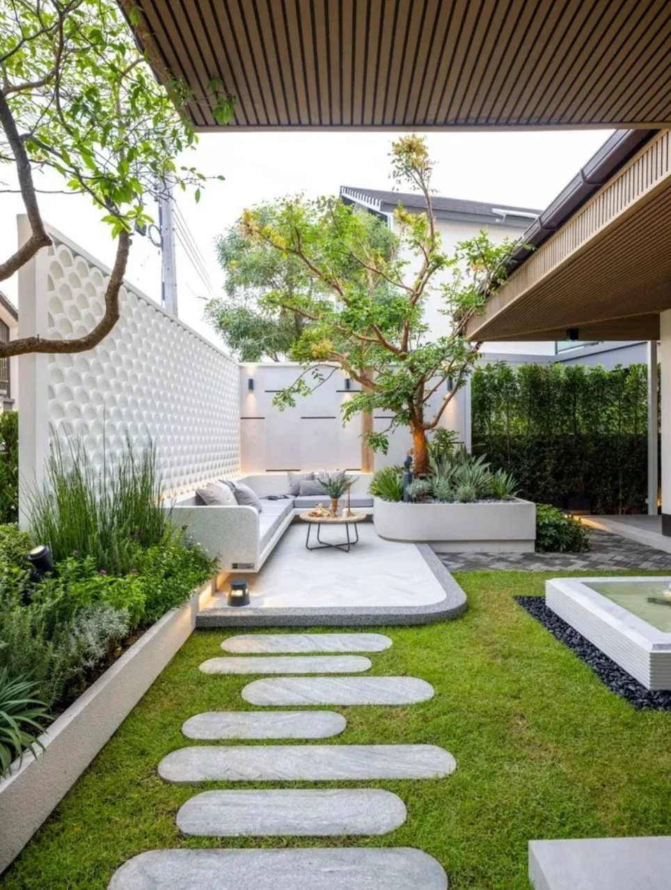 A landscaped courtyard with stepping stones, planted beds and a covered seating terrace.